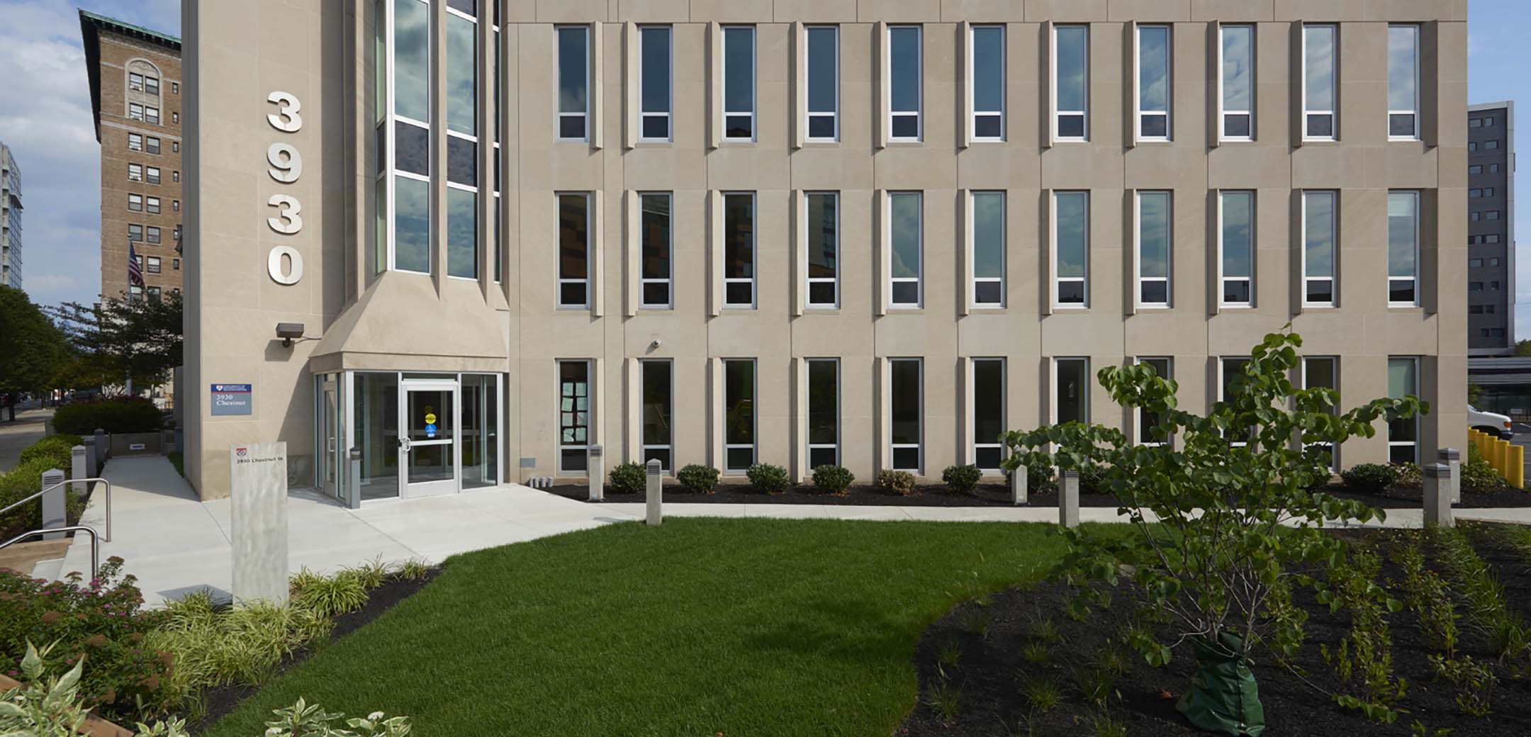A close up view of the 3930 Chestnut building main entrance showcasing the front walkway and grass lawn.
