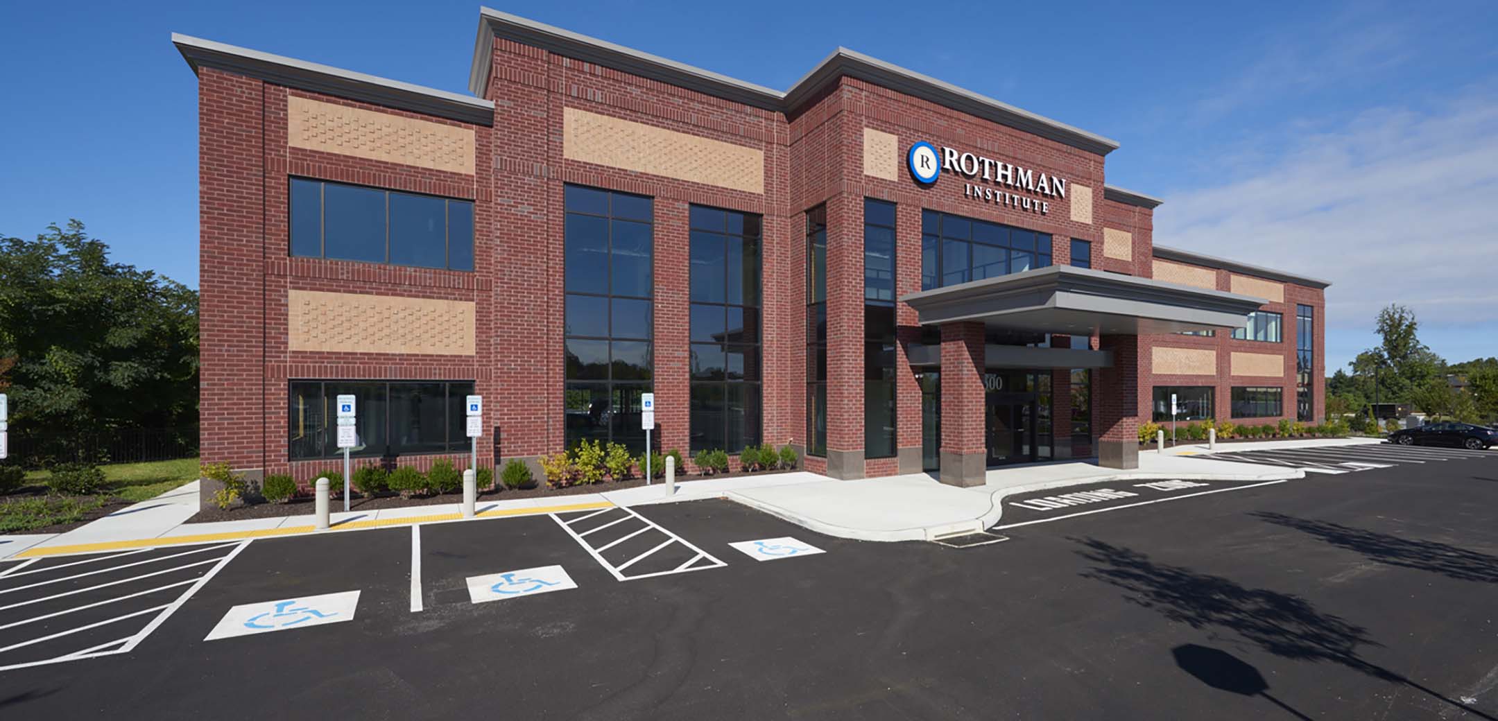An angled view of the Rothman Brinton Lakes red brick building showcasing the front parking lot and main entrance.