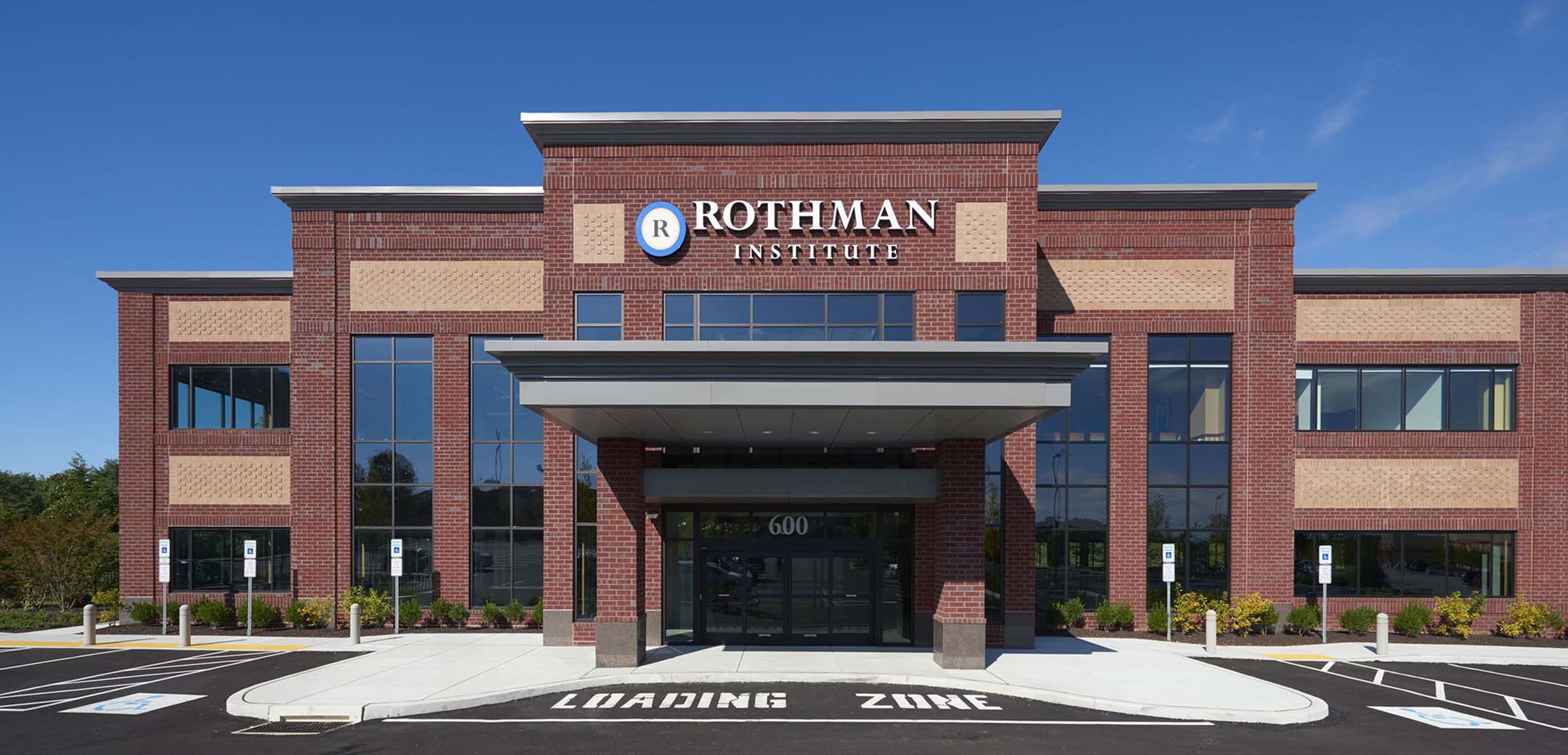 The exterior of the Rothman Brinton Lakes red brick building front entrance showcasing the stepped design and entrance overhang.