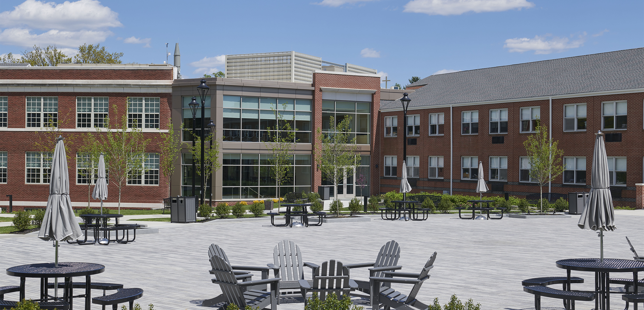 An image of the Malvern Prep school inner courtyard featuring brick flooring and outdoor patio seating with tables and chairs.