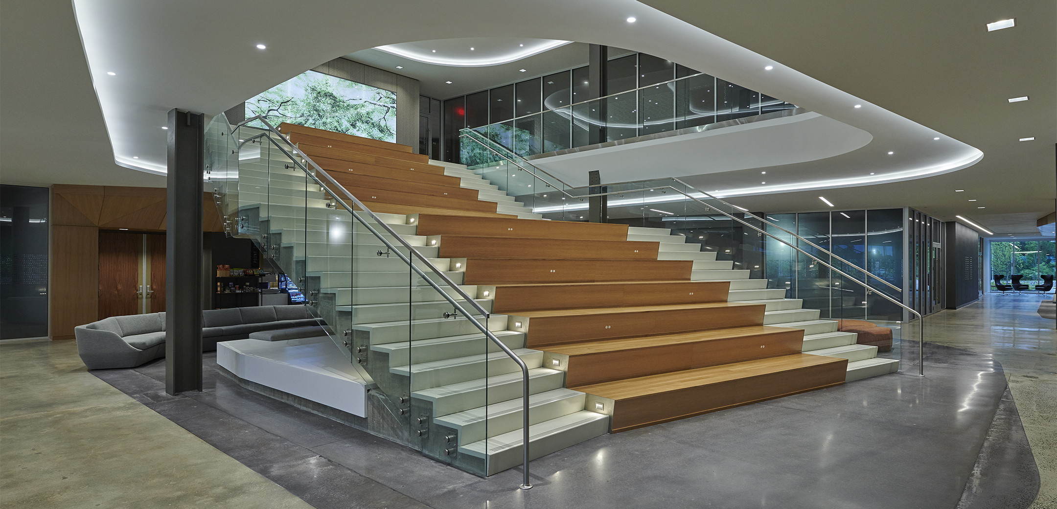 The interior lobby of Arborcrest Corporate Campus featuring grand stair of custom terrazzo in the center and conference rooms and a sitting area in the background.
