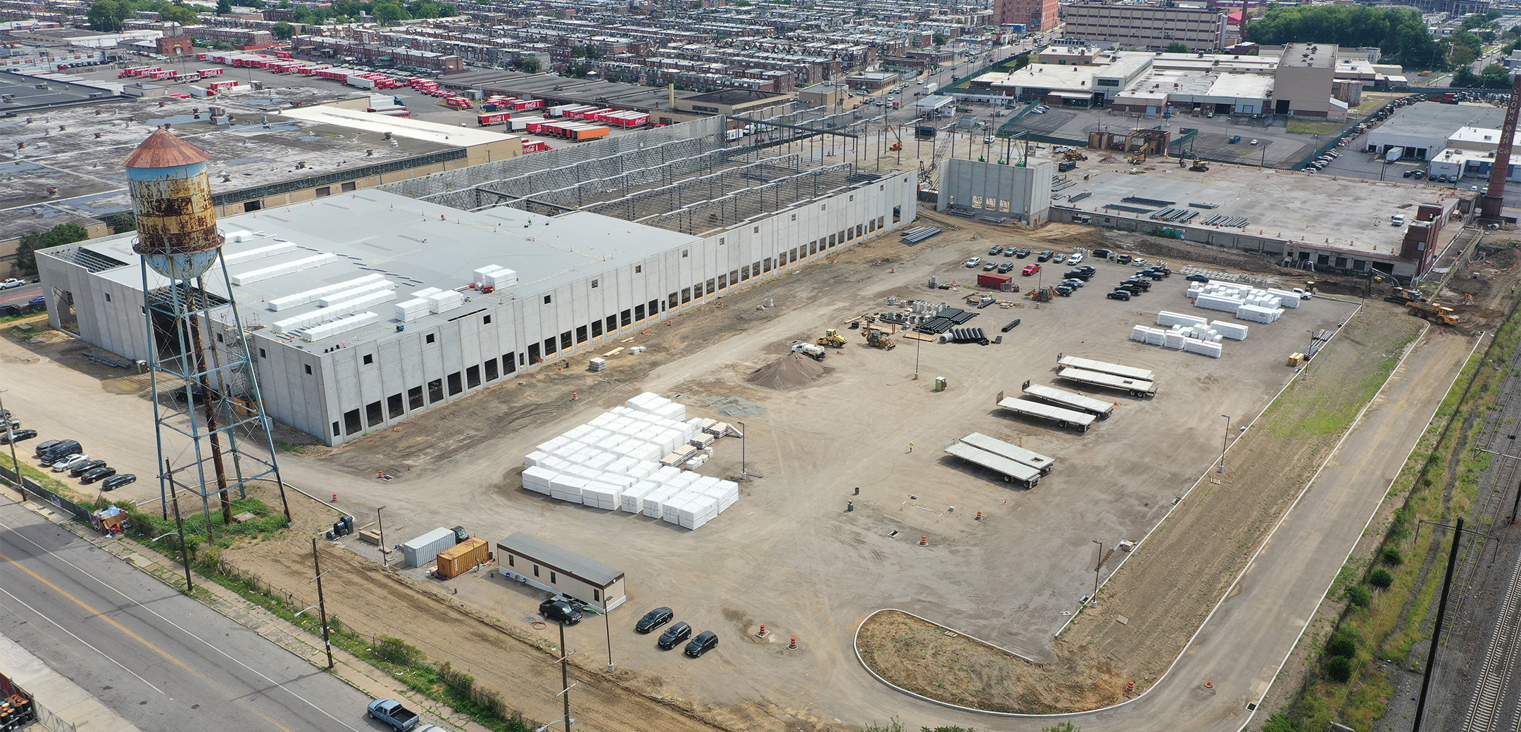 An aerial view of Crown 95 Logistics featuring the long warehouse building taking half the project site and dirt on the other half with construction equipment