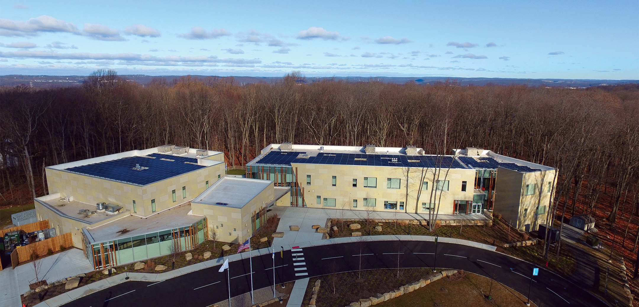 A drone aerial image of the Gottesman RTW Academy building showcasing the layout, woods in the background and front driveway.