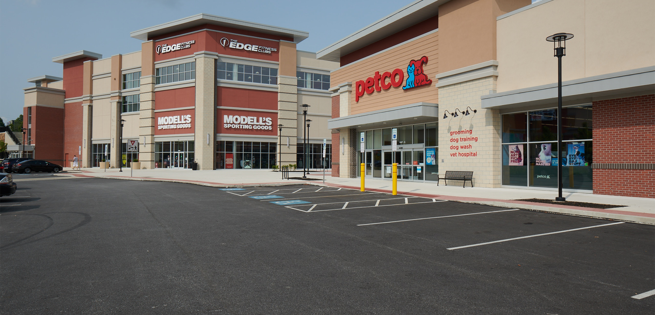 An angled view of the Promenade at Granite Run red and tan brick building, showcasing the "Petco" and "modell's" signage and front parking lot.