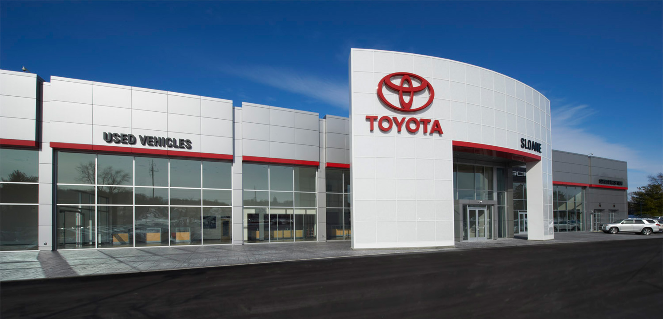 An exterior view of the Sloane modern grey panel building with the "Toyota" signage and logo on the front with large showcase windows peering inside.