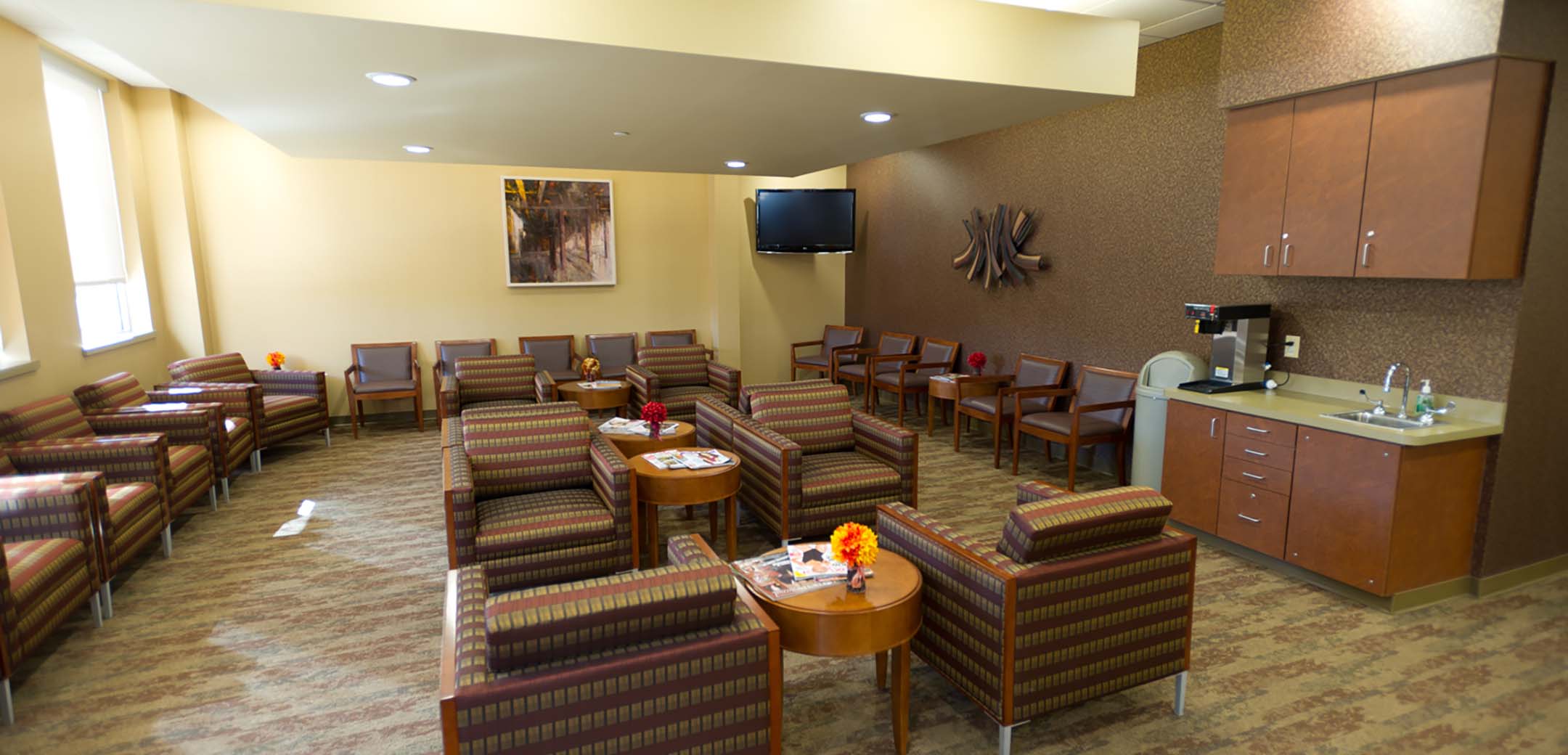 An interior view of the Physician Care Surgical hospital patient seating area, showcasing the many chairs and kitchenet.