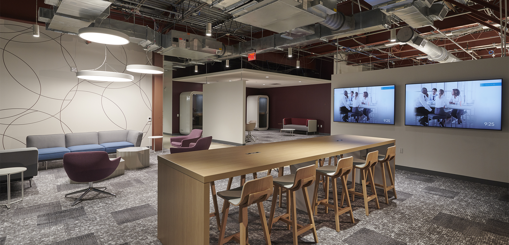 The interior space of Signant Health Headquarters featuring a long table with chairs, tv screens, and a sitting area.