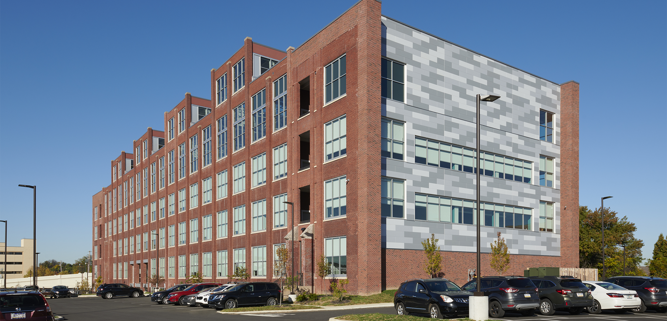 An angled view of a five-story, Class A, brick office building for UGI Energy Services with multiple windows and a metal panel-clad side exterior in the The Knitting Mills mixed-use campus.