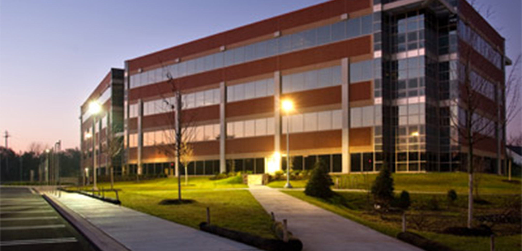 The back side exterior of a 4 story Floral Vale building during dusk featuring the backside parking lot view.