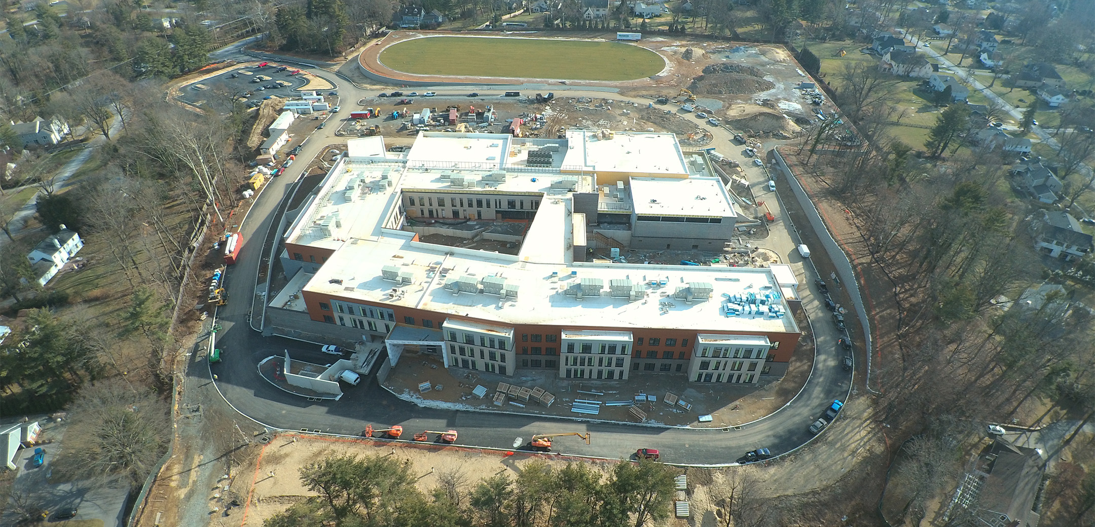 An aerial drone shot of the construction site of Black Rock Middle School showing a large buildings connected with a football field.