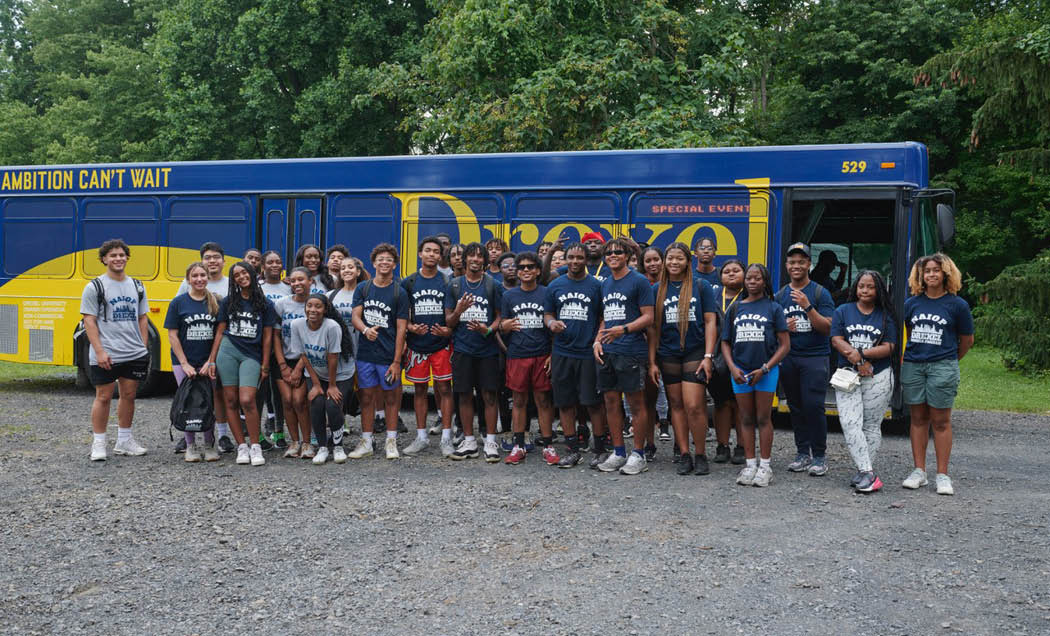 A group of NAIOP Real Estate Summer Program students posing in front of a bus with the Drexel University on it