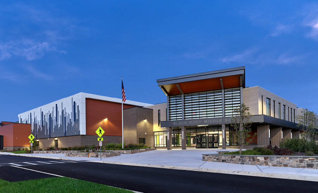 The front of Black Rock Middle School featuring a large brick building and wood facade